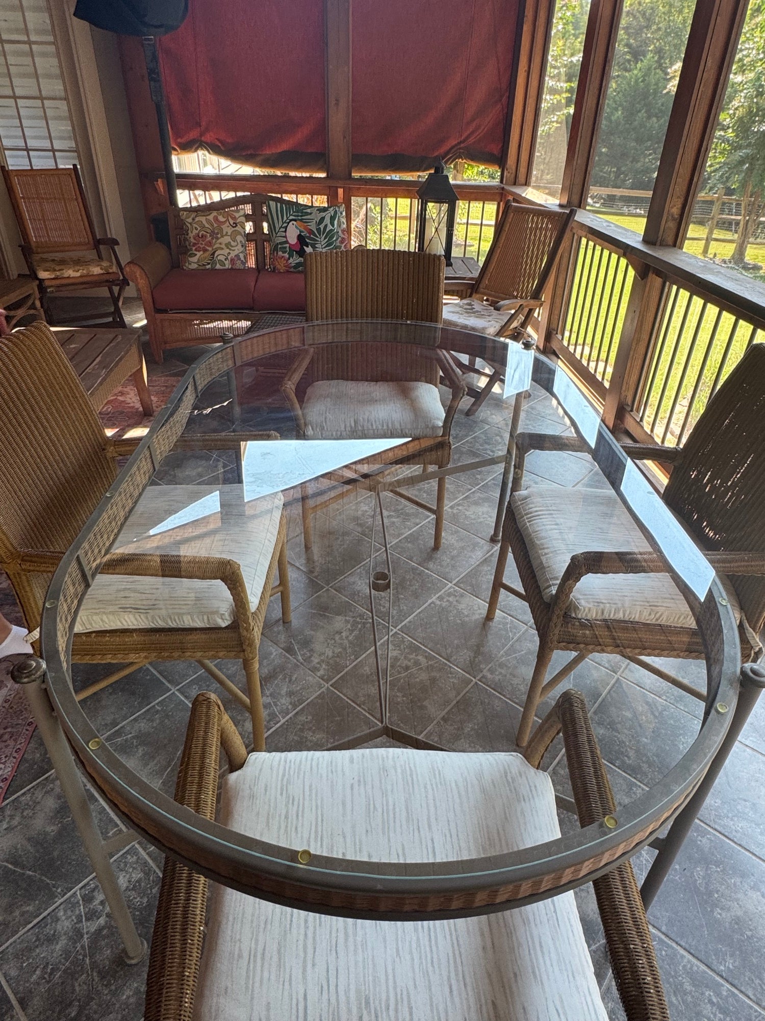 Overhead view of complete dining set showing oval glass table and five wicker armchairs arranged around it