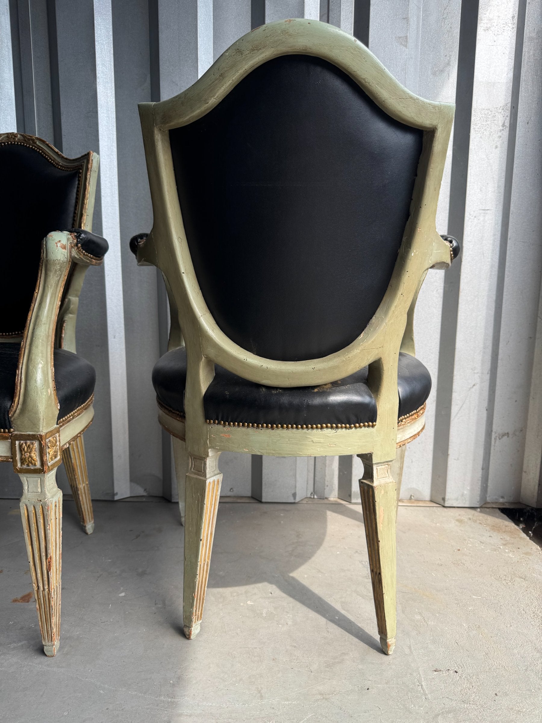Single fauteuil chair rear view showing oval backrest with black leather panel and painted wooden frame with distressed finish