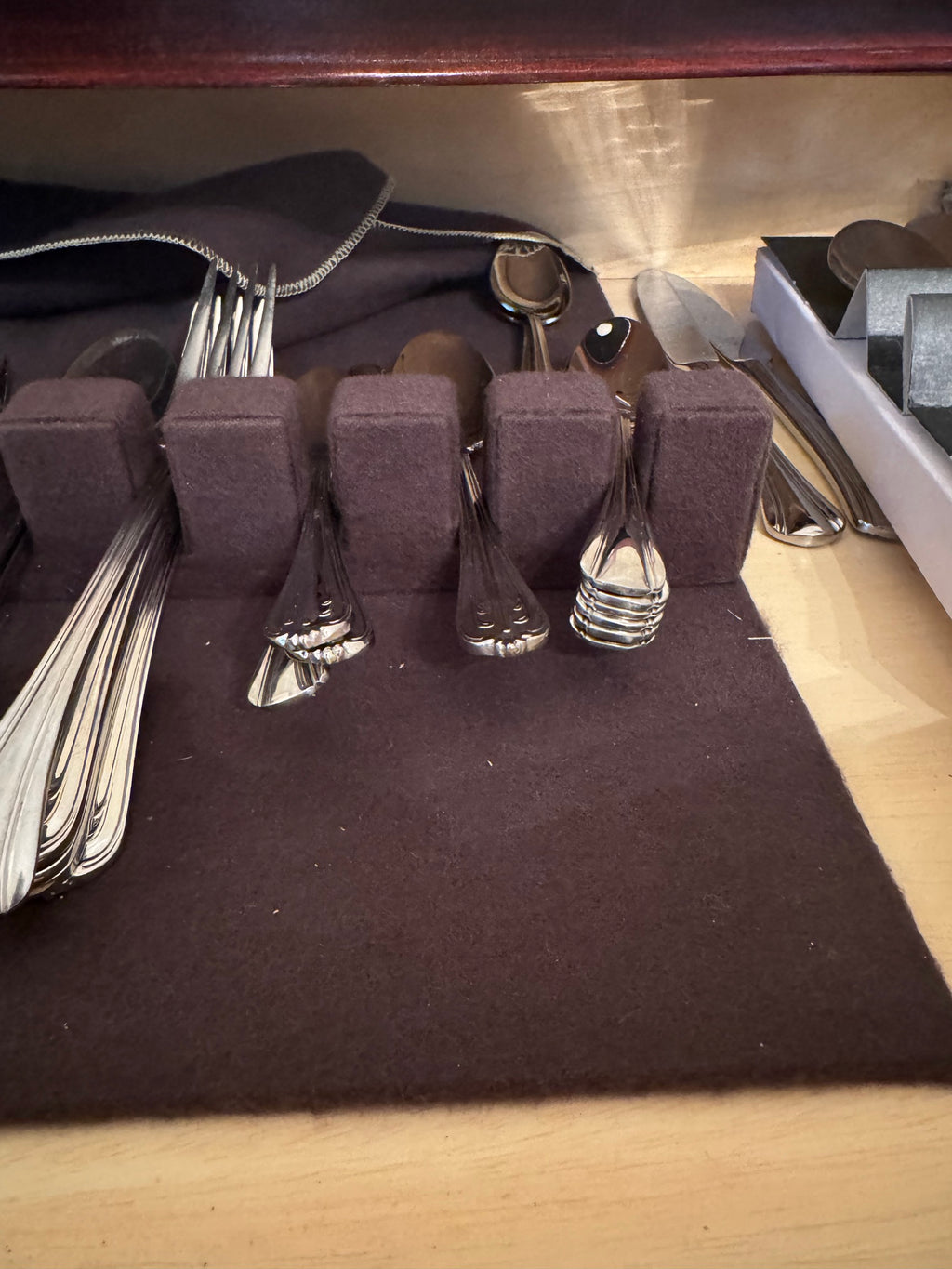 Flatware chest tray with empty felt slots and remaining forks, spoons and knives