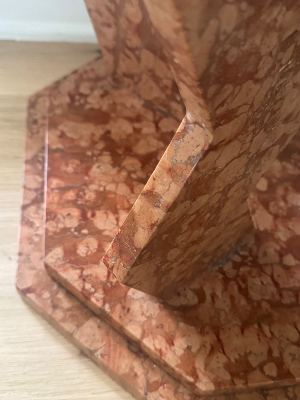Close-up detail of red and tan tessellated marble pattern on pedestal leg, showing natural veining and surface texture