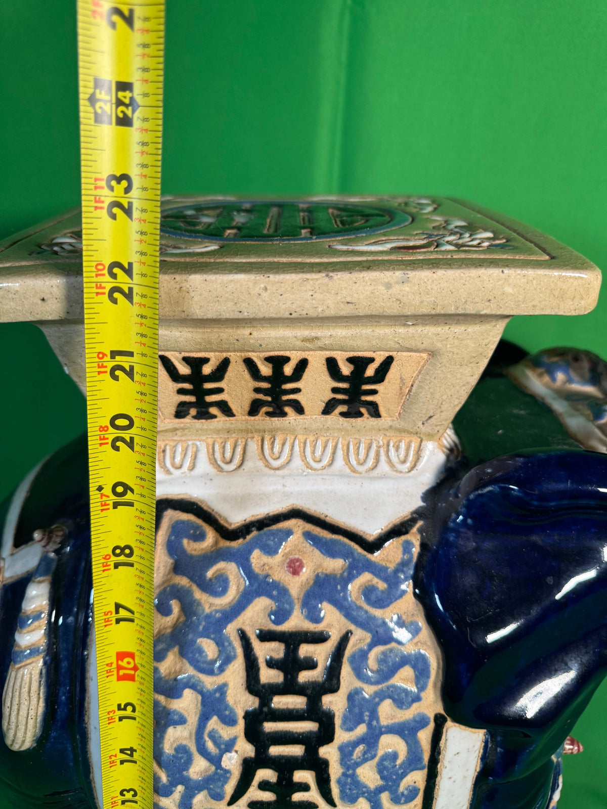 Full view of large cobalt elephant garden stool with gilt accents, cream elephant stools displayed in front, interior setting