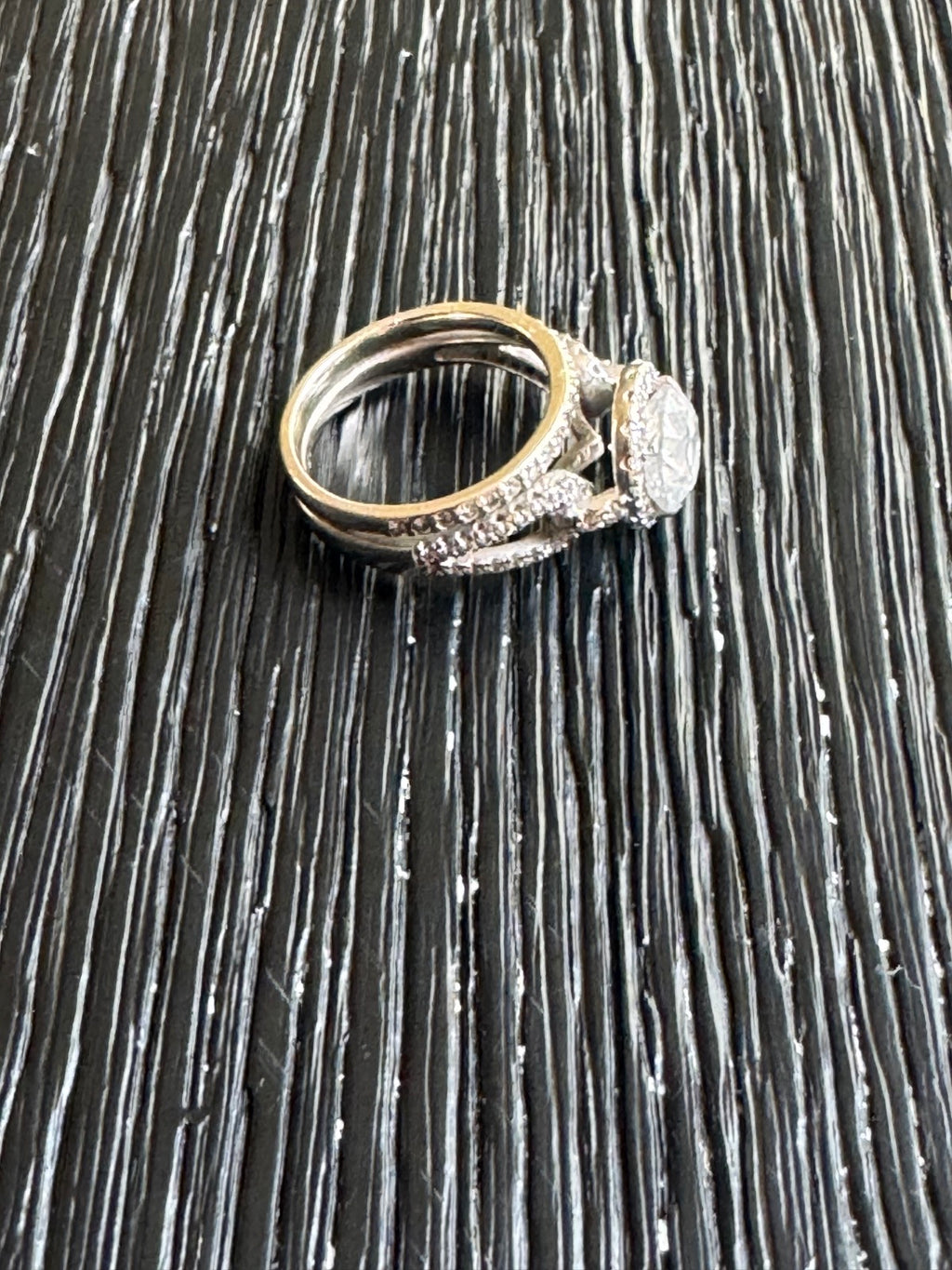 Complete engagement ring and matching band set displayed on dark textured surface, side view