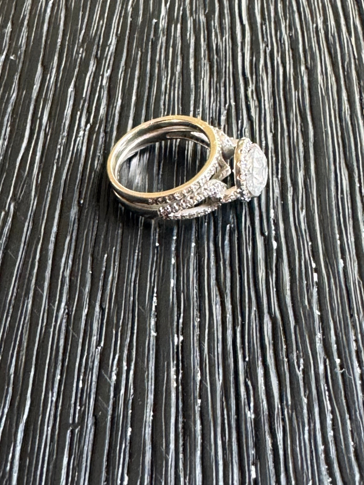 Complete engagement ring and matching band set displayed on dark textured surface, side view