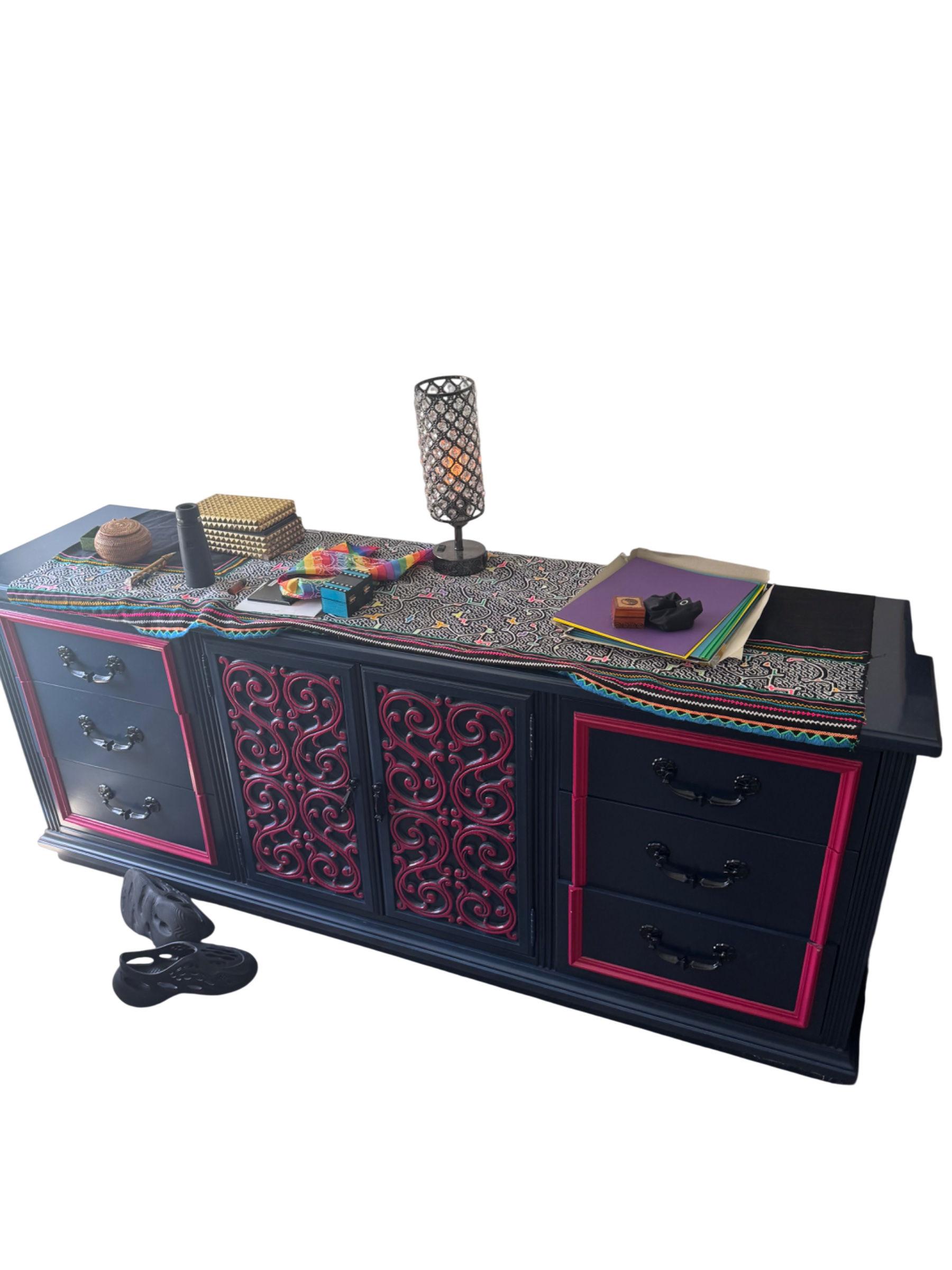 Black credenza with pink trim and ornate carved door panels, styled desktop with colorful accessories and lamp