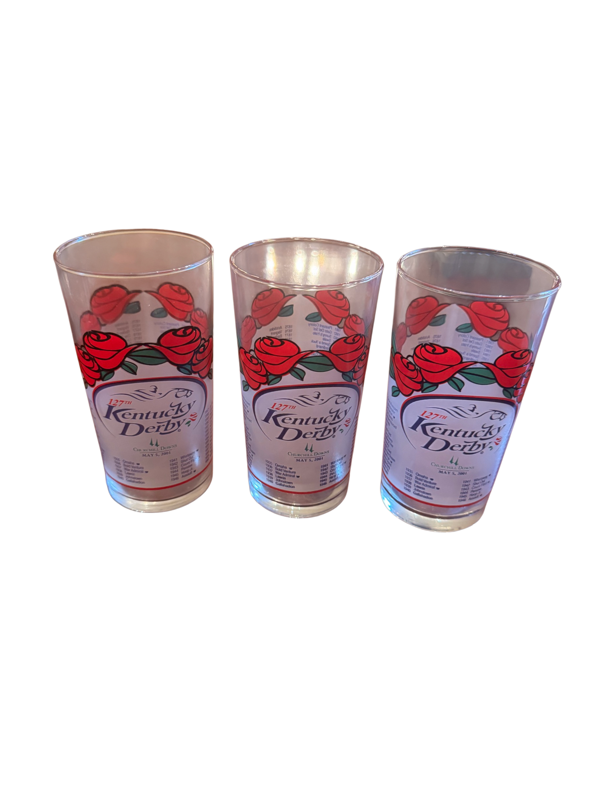 Three Kentucky Derby 127th 2001 commemorative glasses with red rose design on a wood table