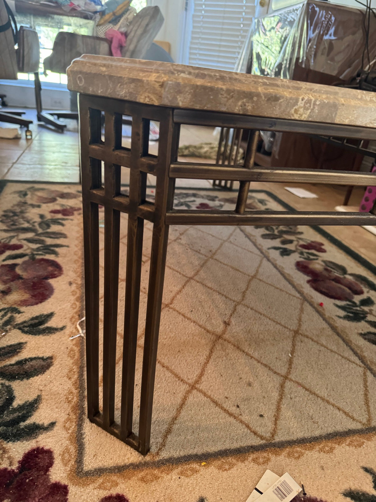 Side of the coffee table showing the bronze-tone metal bar base