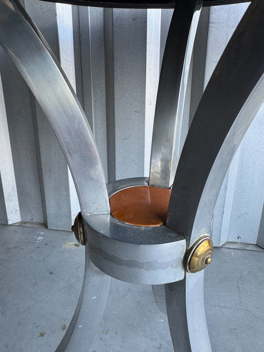 Chrome curved base legs with metal band clamp and brass cap feet, underside view of table structure