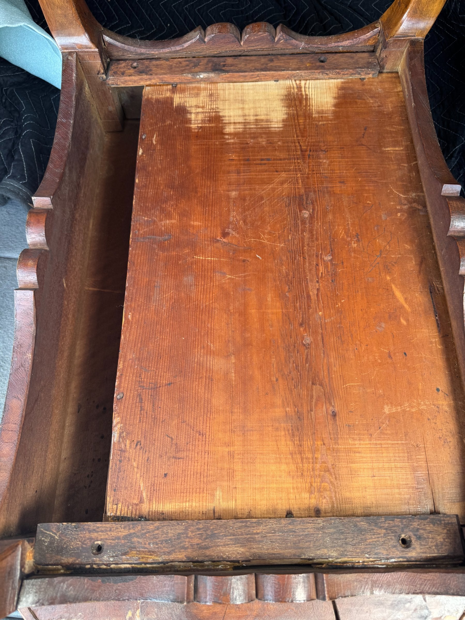 Interior view of open drawer showing wooden base and light wood interior construction