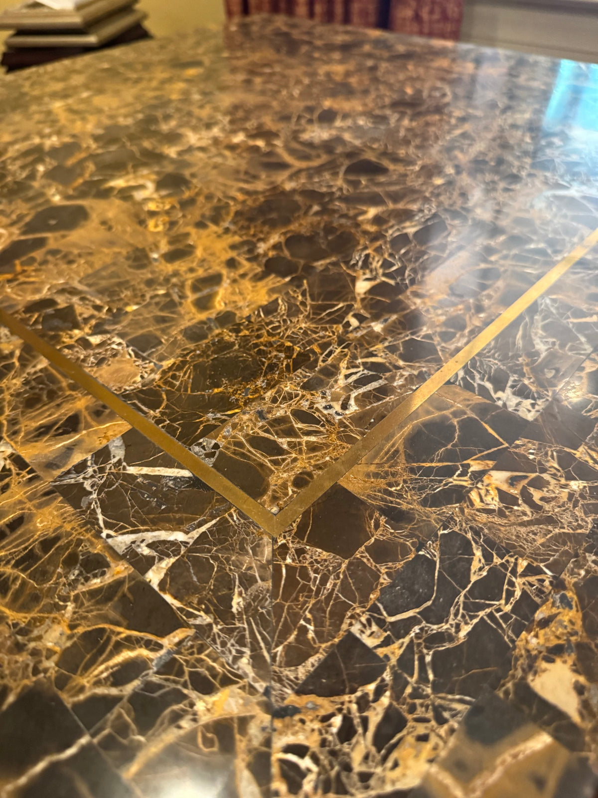 Close-up of black and gold marble top surface showing intricate veining pattern and brass inlay banding detail