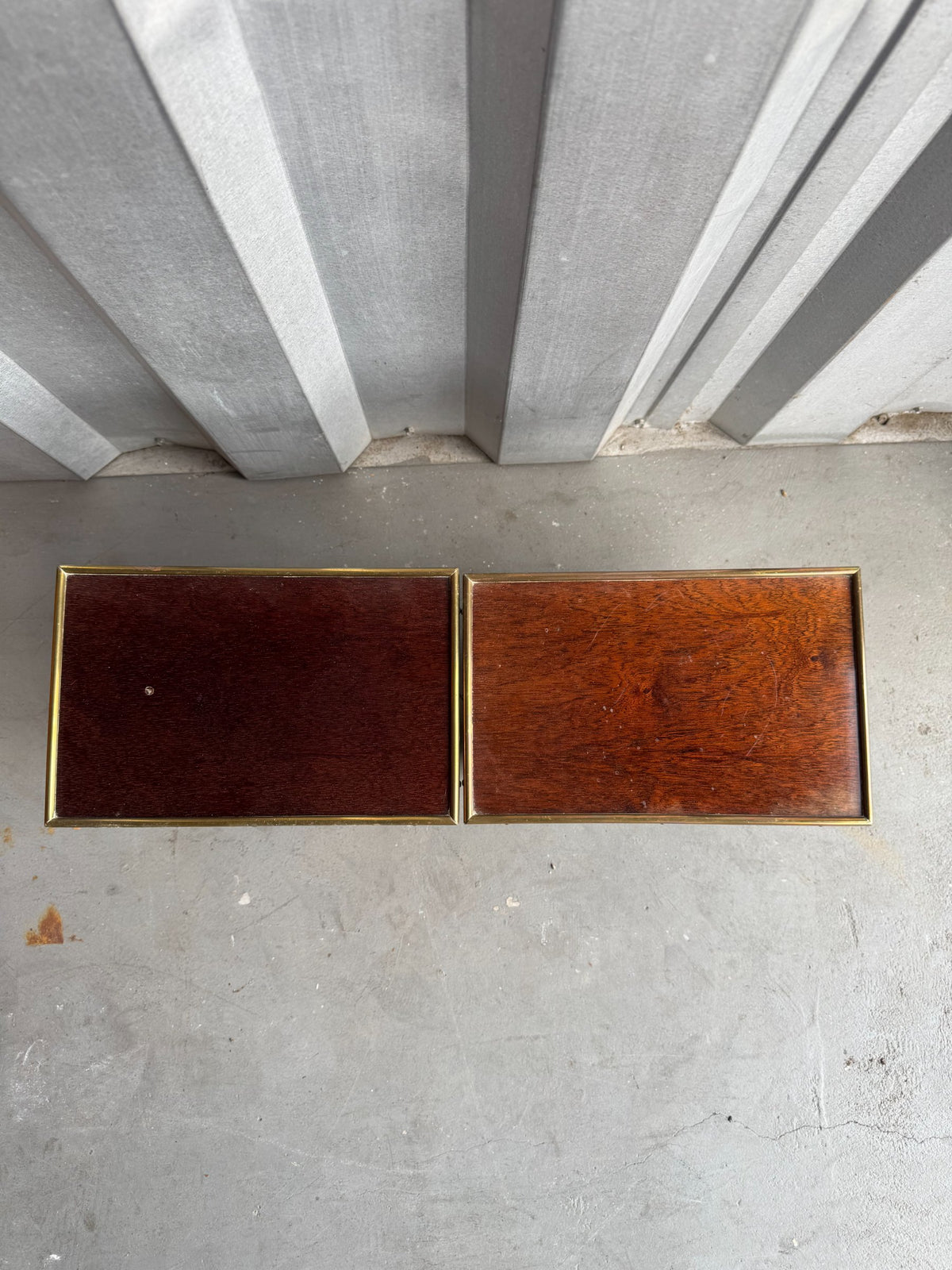 Top-down view of both tables displaying mahogany wood grain and brass-bound edges