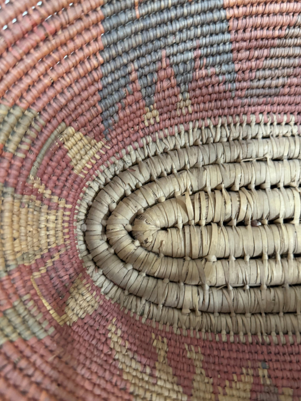 Close-up of woven texture showing tight coiled basketweave pattern in multicolored natural fibers