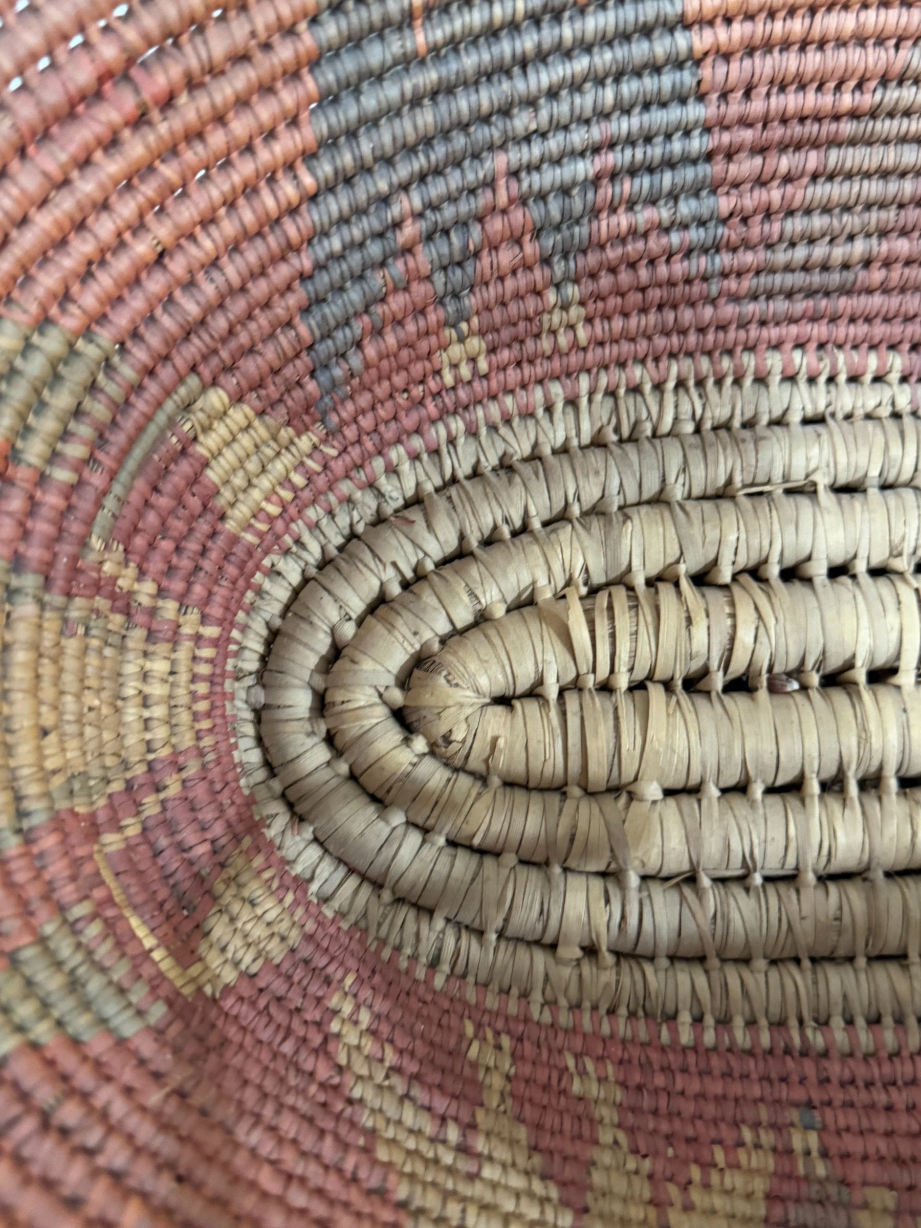Close-up of woven texture showing tight coiled basketweave pattern in multicolored natural fibers