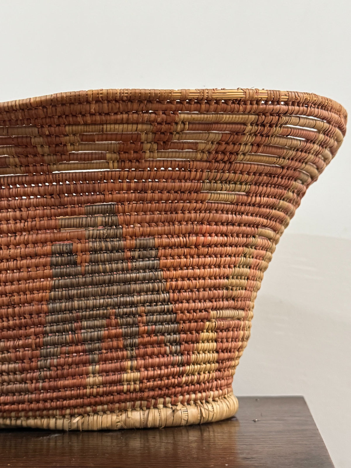 Full basket from side angle displaying gently sloped walls and handle placement on tan surface