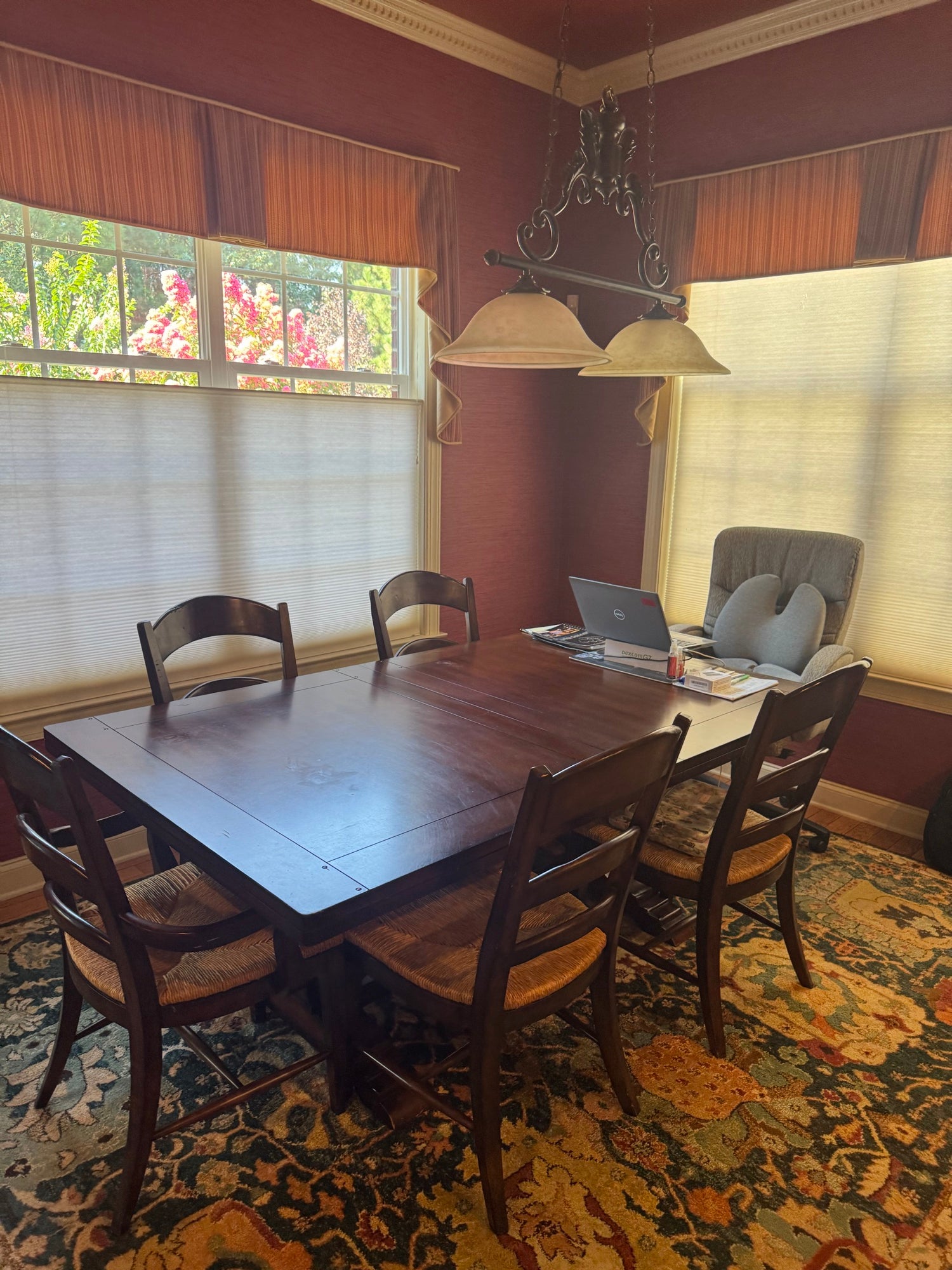 Broyhill dining table with six chairs and decorative pendant lighting in warm burgundy room with windows