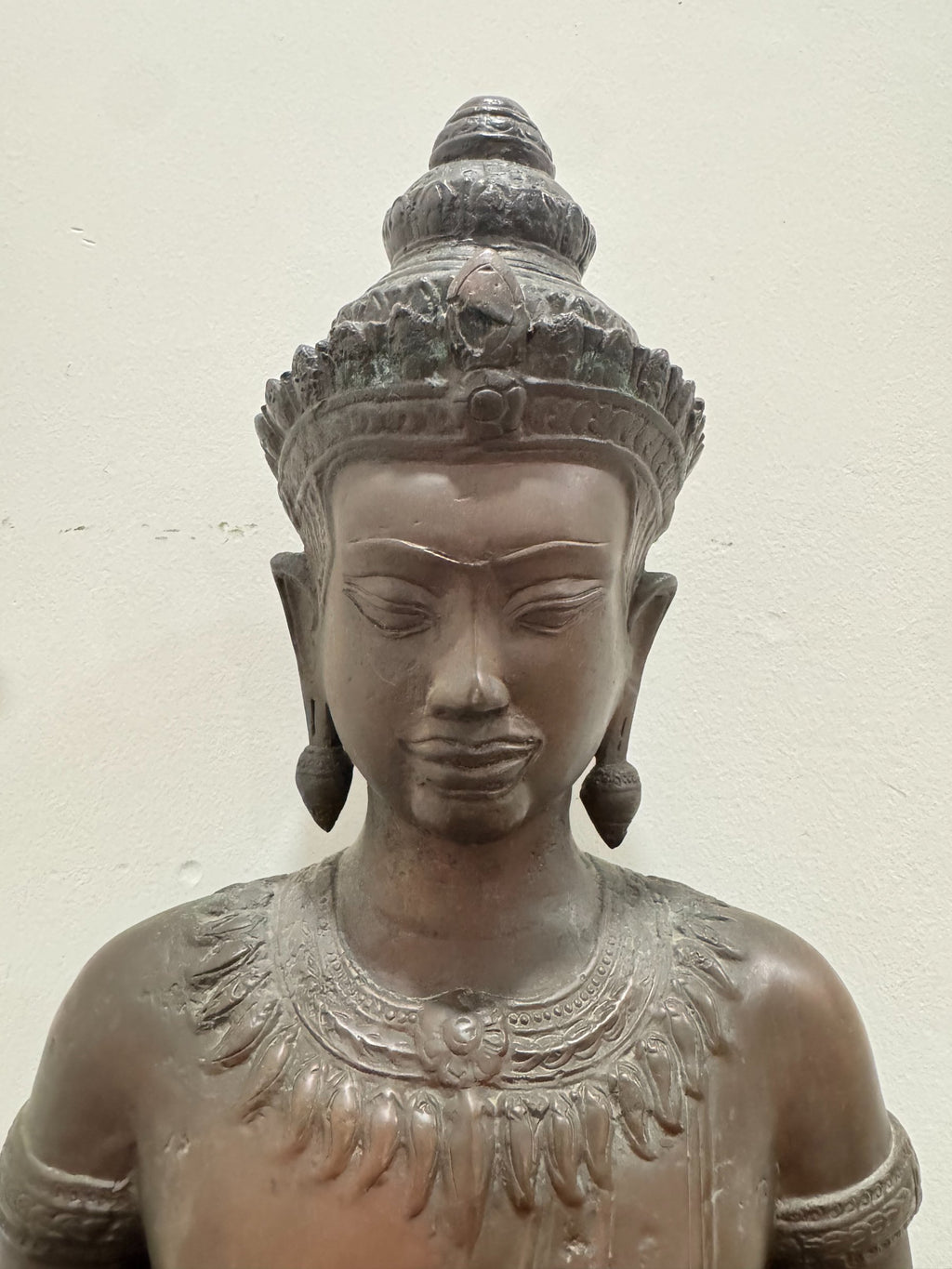 Buddha head and shoulders, front-facing, showing serene expression, elaborate tiered crown, elongated earlobes