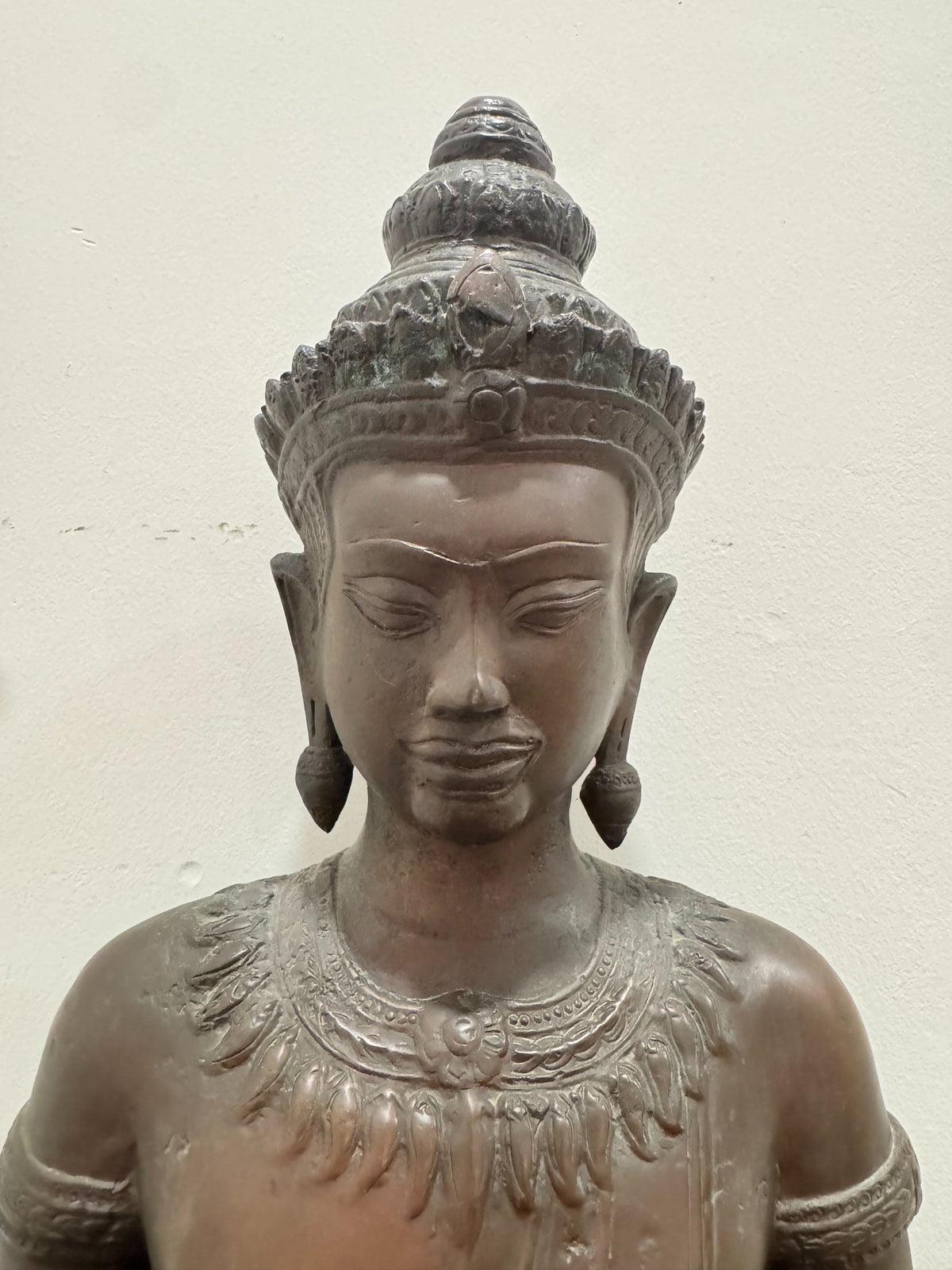 Buddha head and shoulders, front-facing, showing serene expression, elaborate tiered crown, elongated earlobes