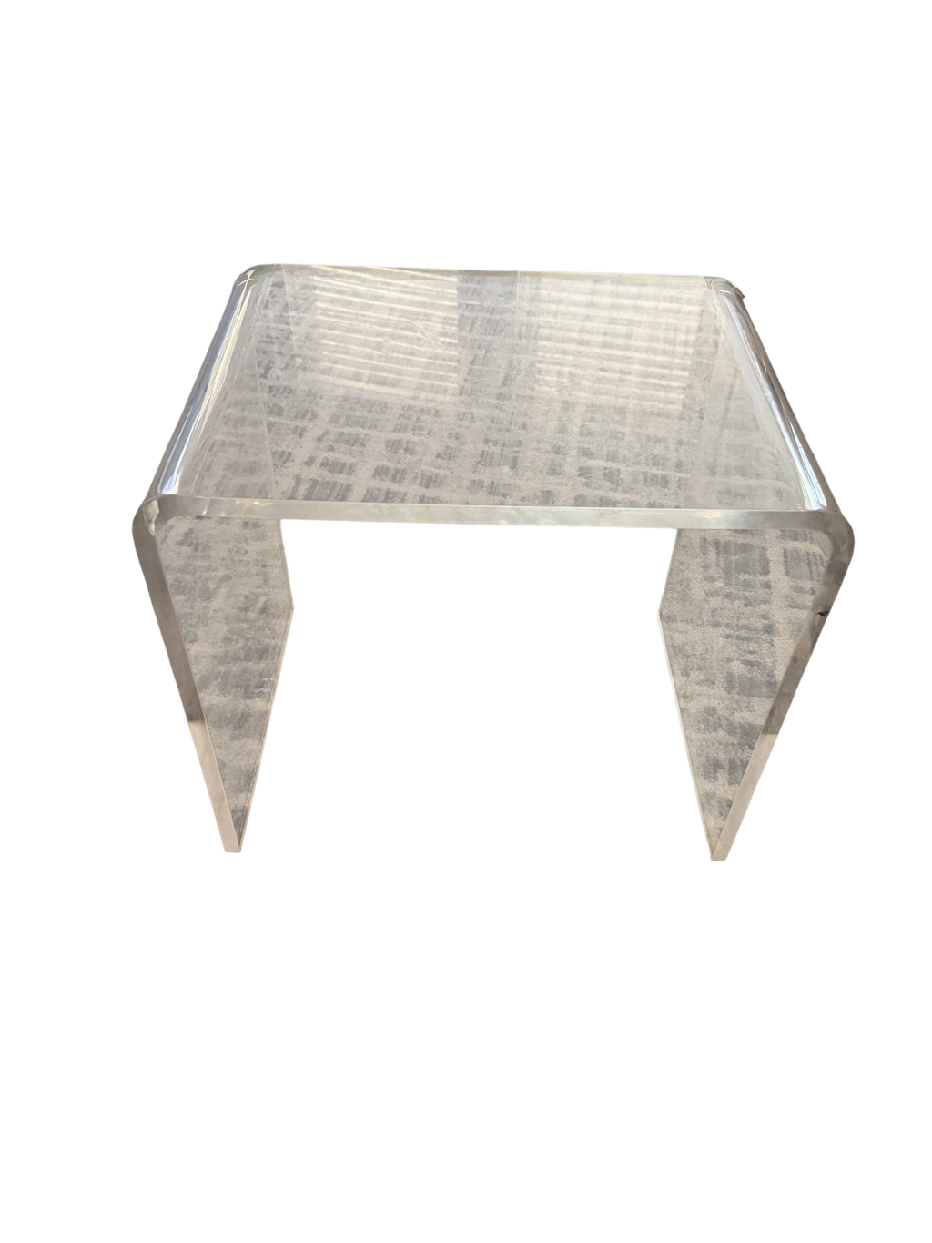 Clear acrylic waterfall coffee table on a patterned rug