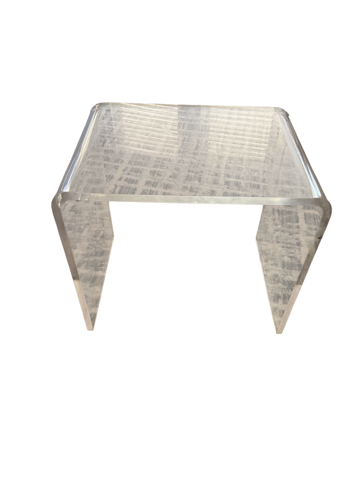 Clear acrylic waterfall coffee table on a patterned rug
