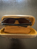 Gucci sunglasses with black frames and dark lenses in open tan velvet-lined case, showing interior view