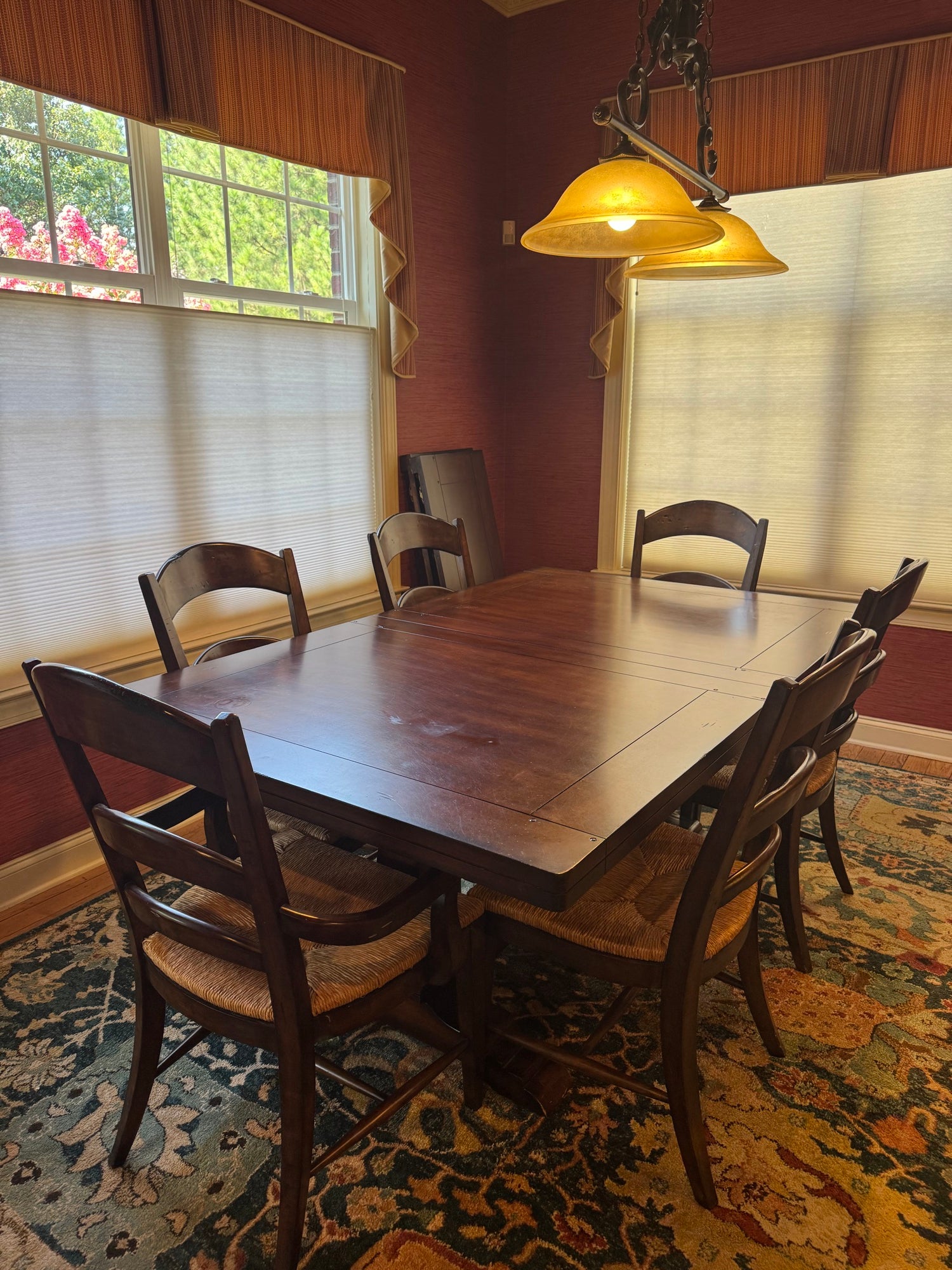 Close-up view of extended table surface with chairs positioned around it, single pendant lamp illuminated