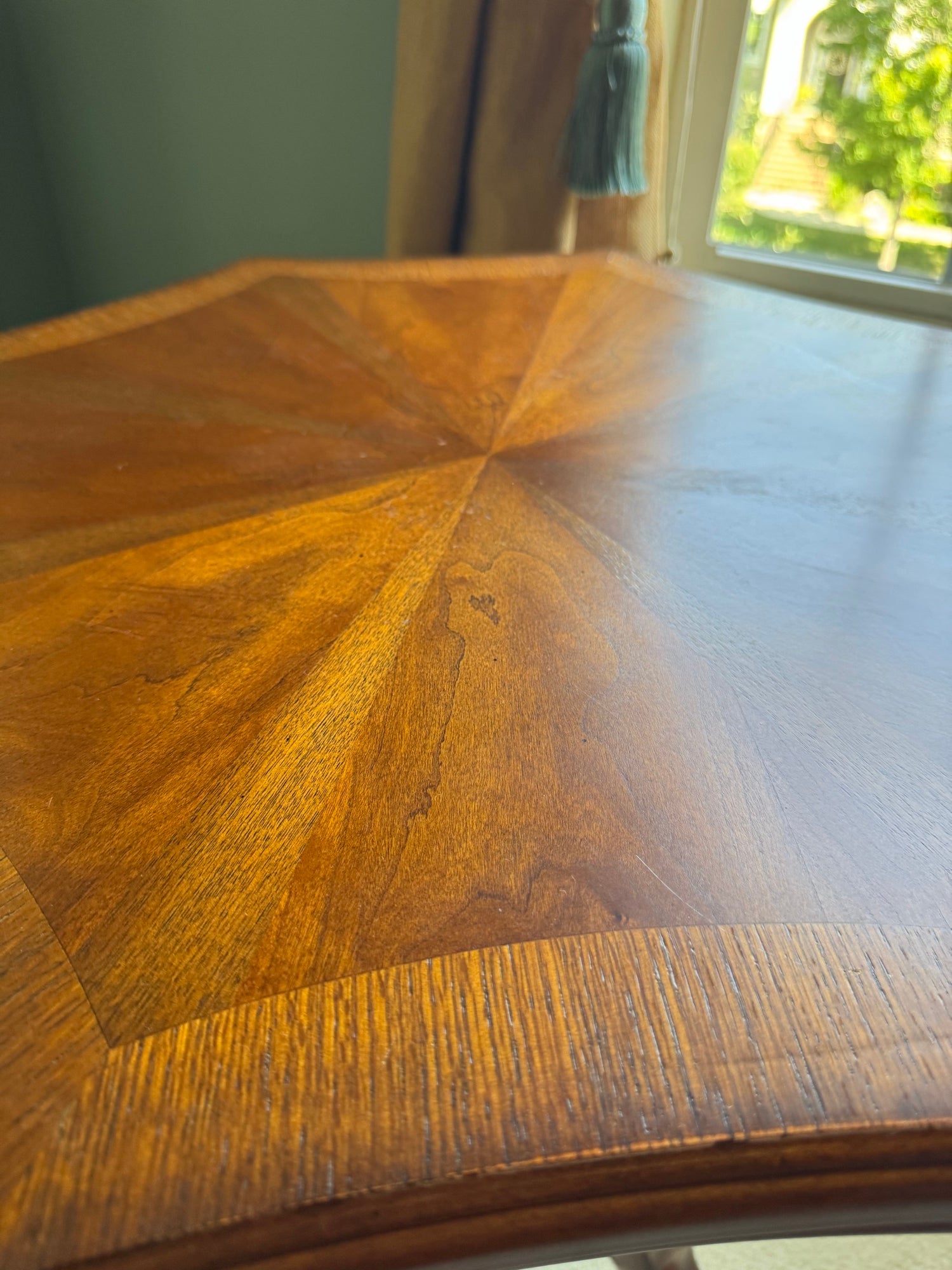 Close-up of sunburst veneer pattern on tabletop showing radiating wood grain and grain variation detail