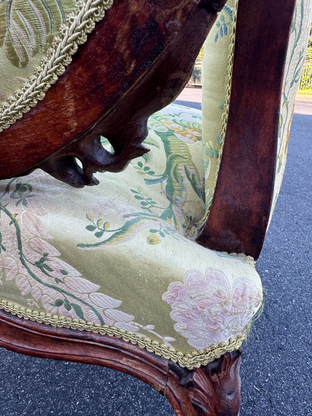 The junction of arm, seat and back, showing the carved uprights and the brocade seat