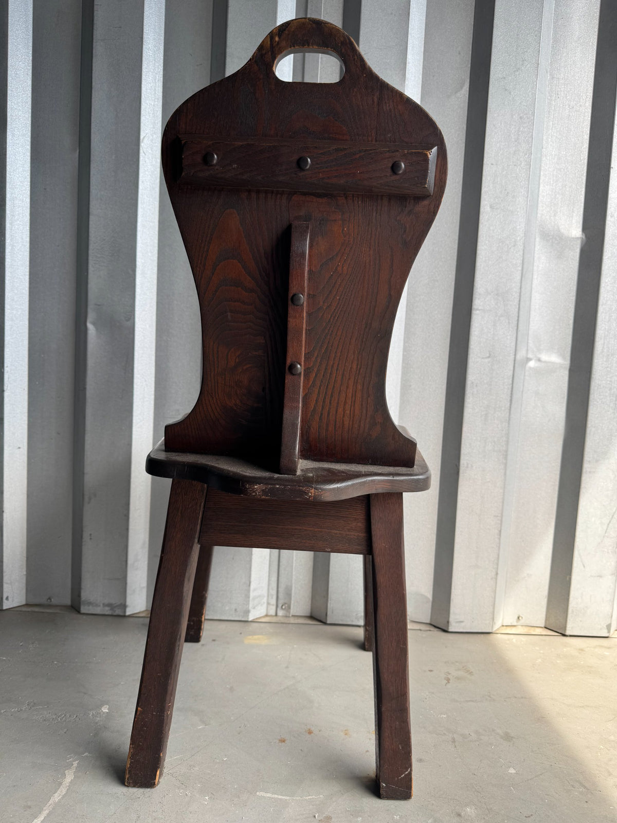 Single chair from front showing tall backrest with oval handle and scalloped apron detail