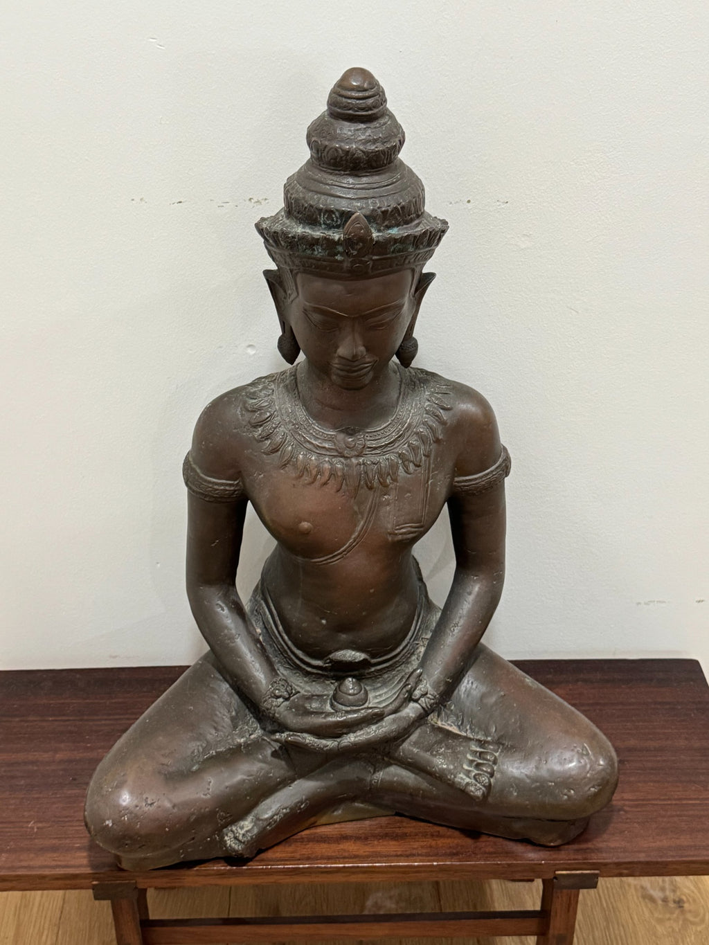 Buddha bust detail showing face, crown, and ornamental necklace with careful carving work