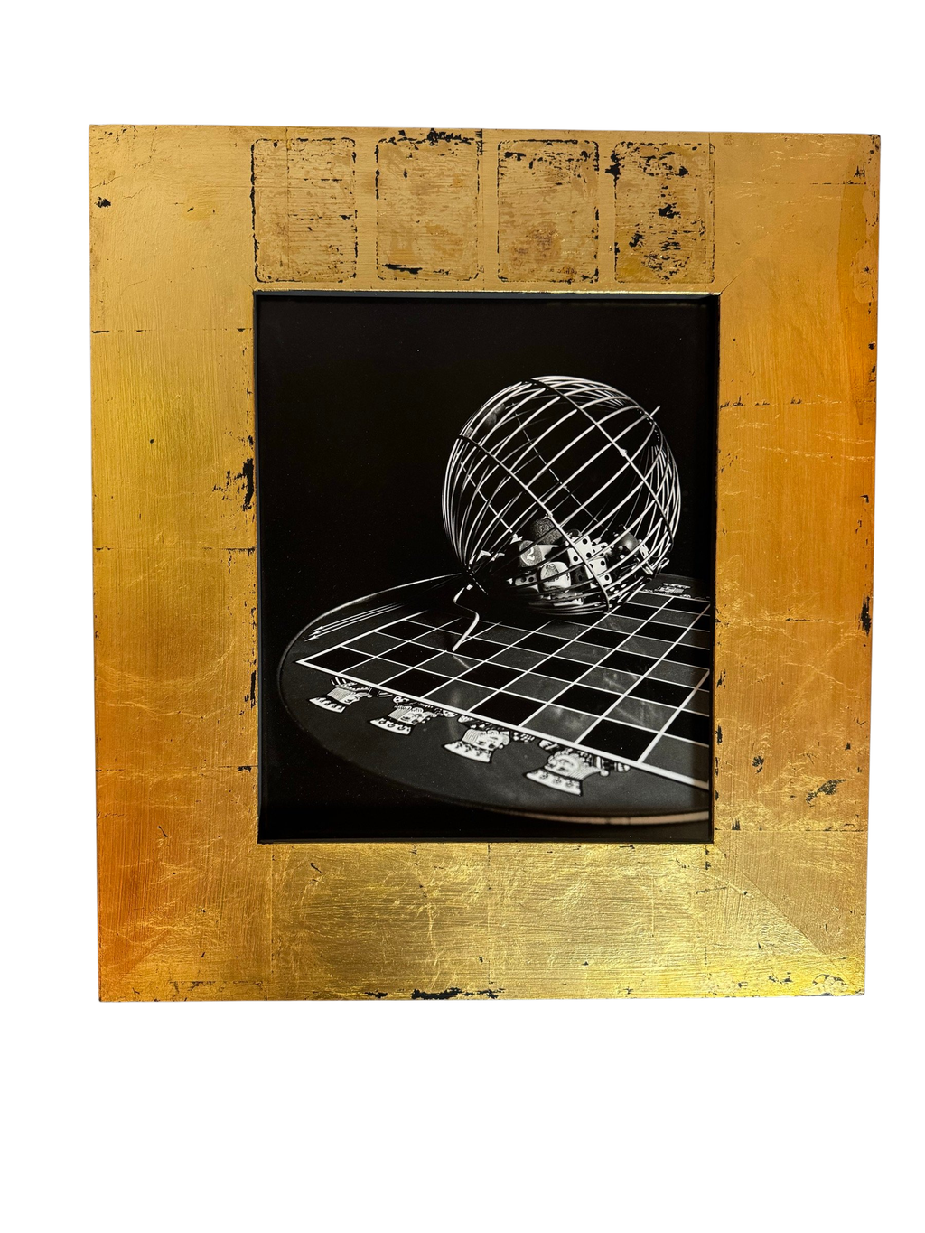Black-and-white photograph of a wire globe on a chessboard in a gold-leaf frame, straight-on view