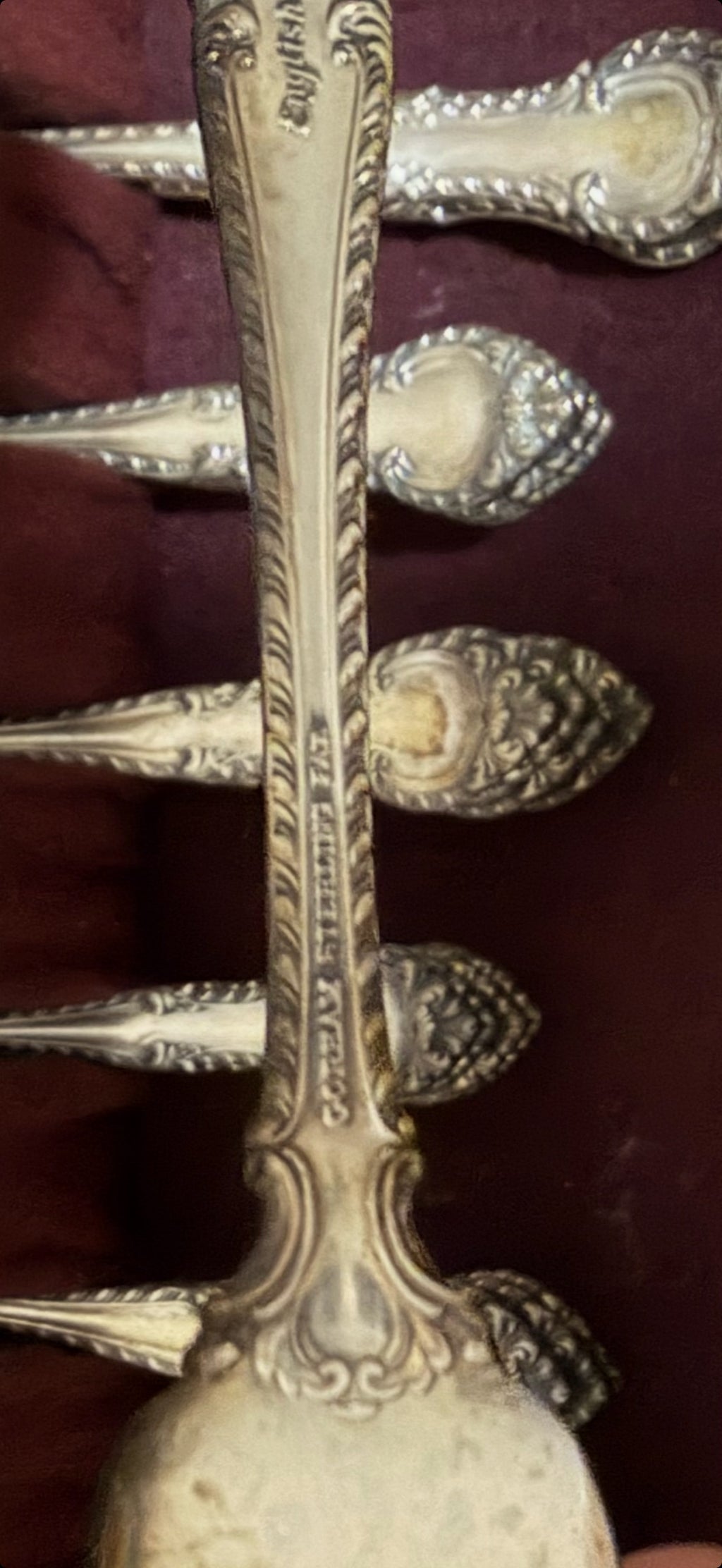 Close-up of ornate sterling handle showing detailed floral and scrollwork engraving on the stem and decorative finial
