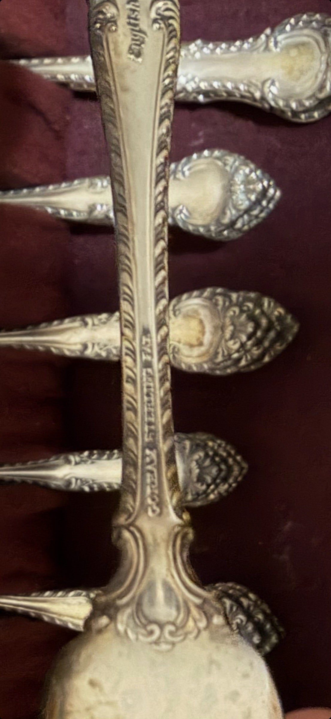 Close-up of ornate sterling handle showing detailed floral and scrollwork engraving on the stem and decorative finial