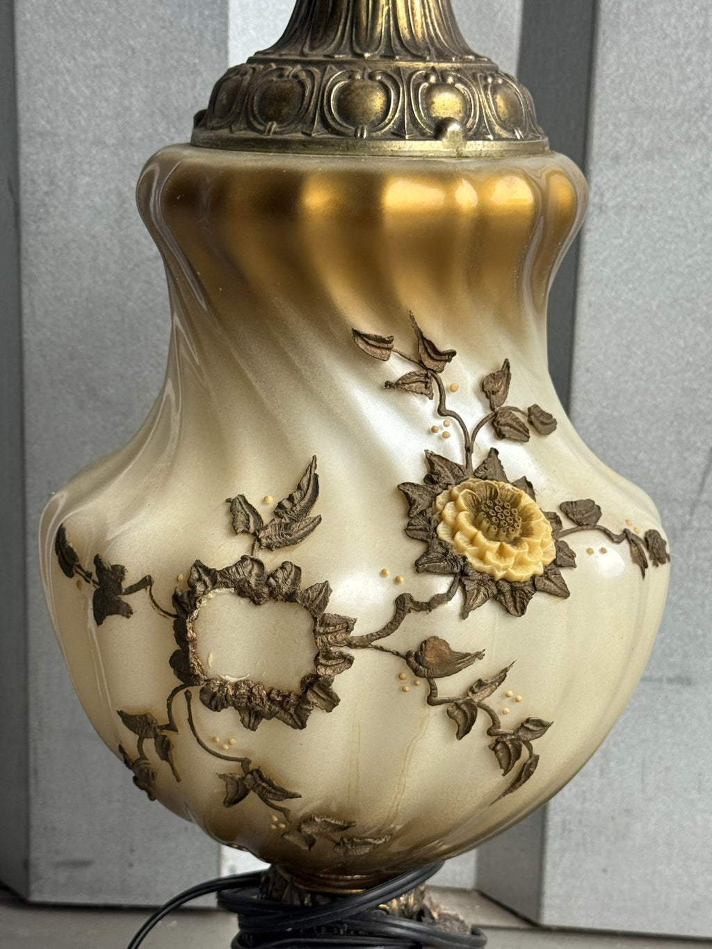 Close-up detail of lamp body showing cream porcelain with gilt and bronze floral relief, featuring sunflower and leaf motifs
