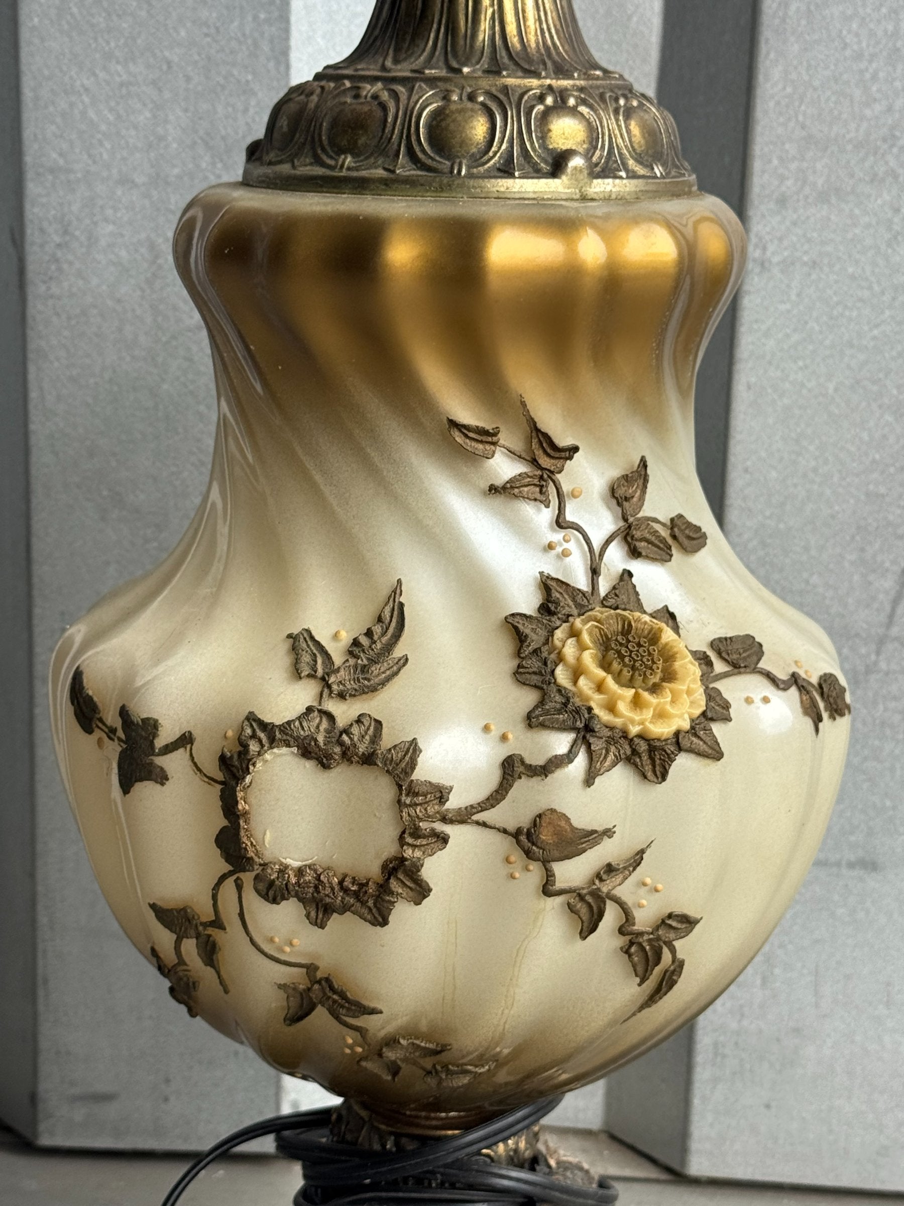 Close-up detail of lamp body showing cream porcelain with gilt and bronze floral relief, featuring sunflower and leaf motifs