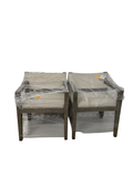 Two wrapped teak outdoor lounge chairs with gray cushions, front view, still in protective plastic packaging