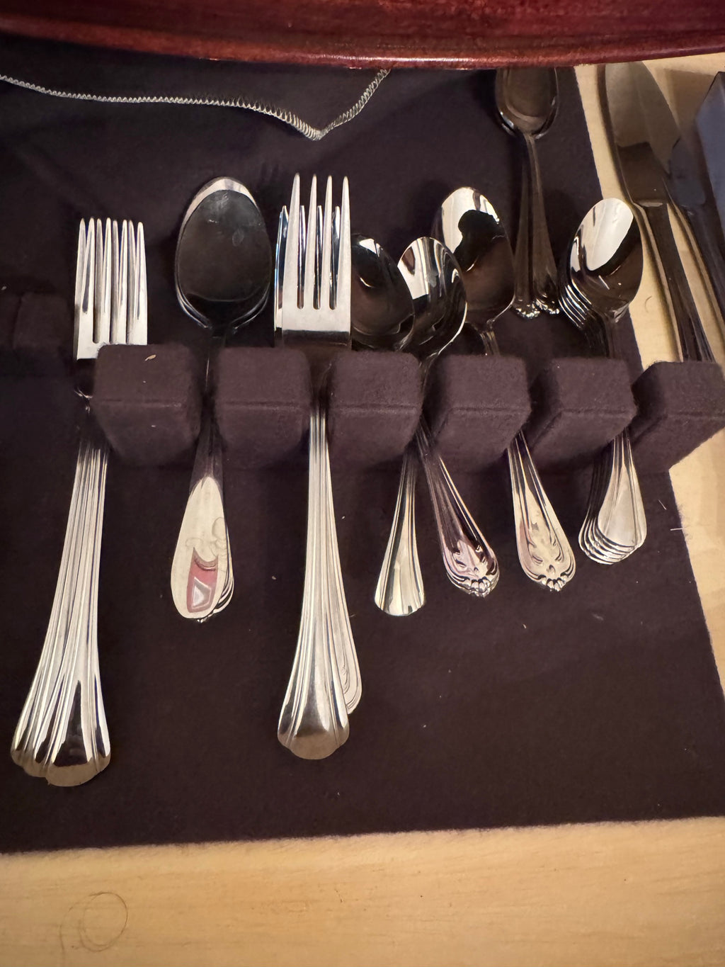 Assorted forks, spoons and knives arranged in felt slots inside the flatware chest