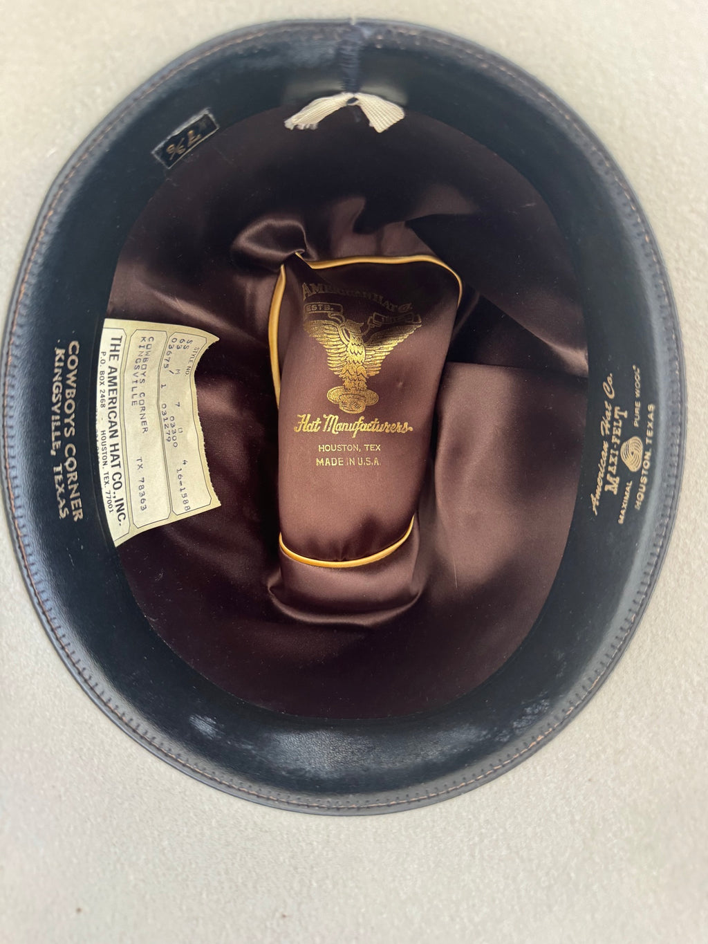 Interior view of black cowboy hat showing brown silk lining and golden eagle manufacturer's label