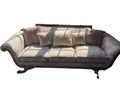 Full front view of floral damask sofa with rolled arms, three cushions, decorative pillows, and ornate wooden frame in bright natural light