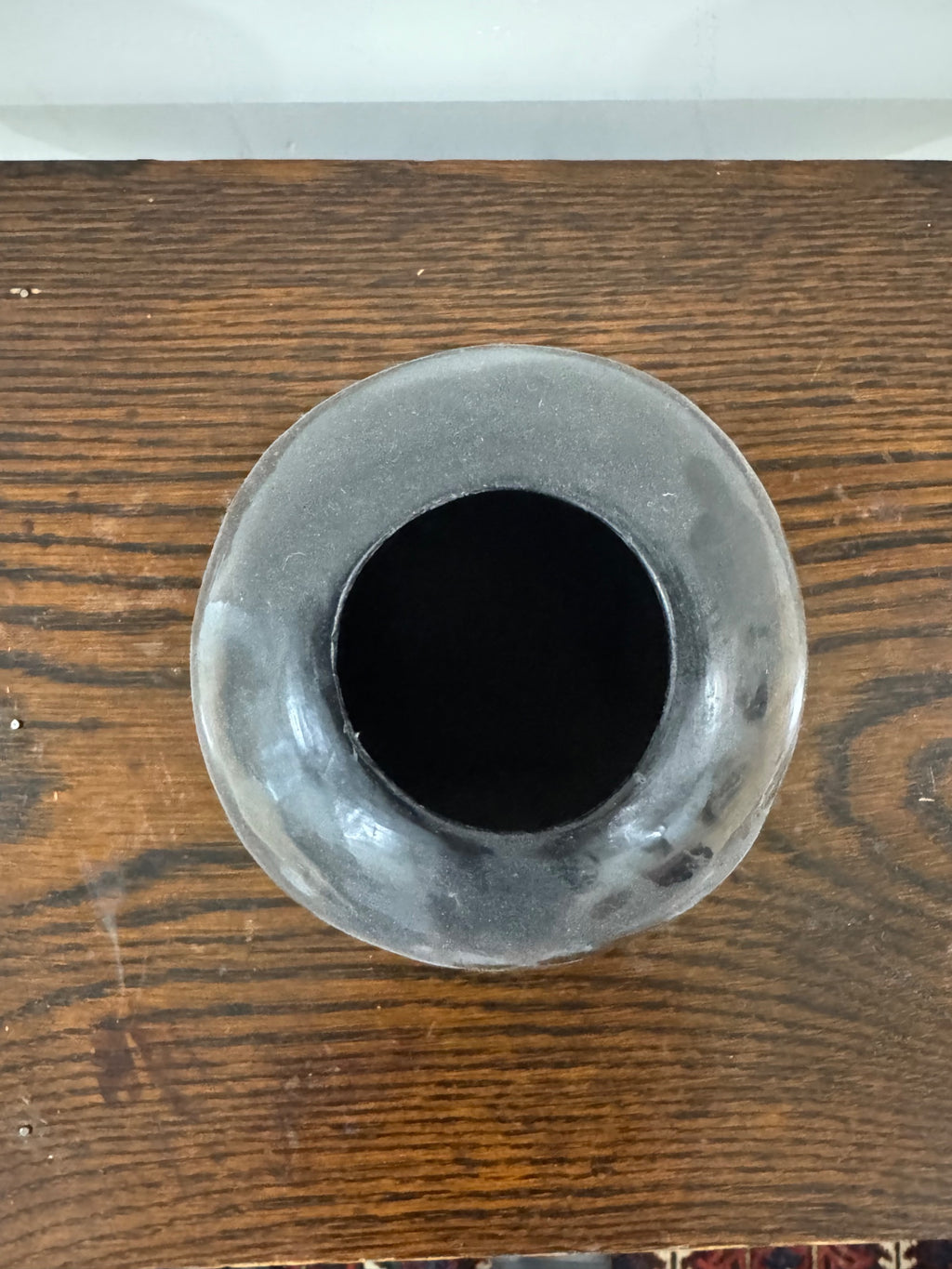 Top-down view of vase opening showing circular rim and deep interior cavity, polished dark ceramic material visible