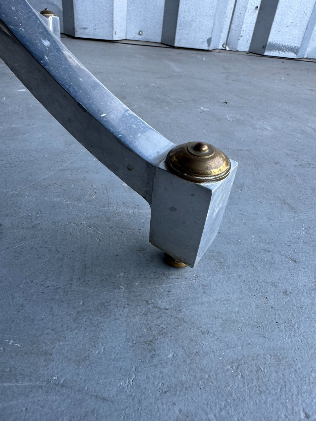 Single brass cap detail on curved chrome leg foot, close-up of hardware attachment