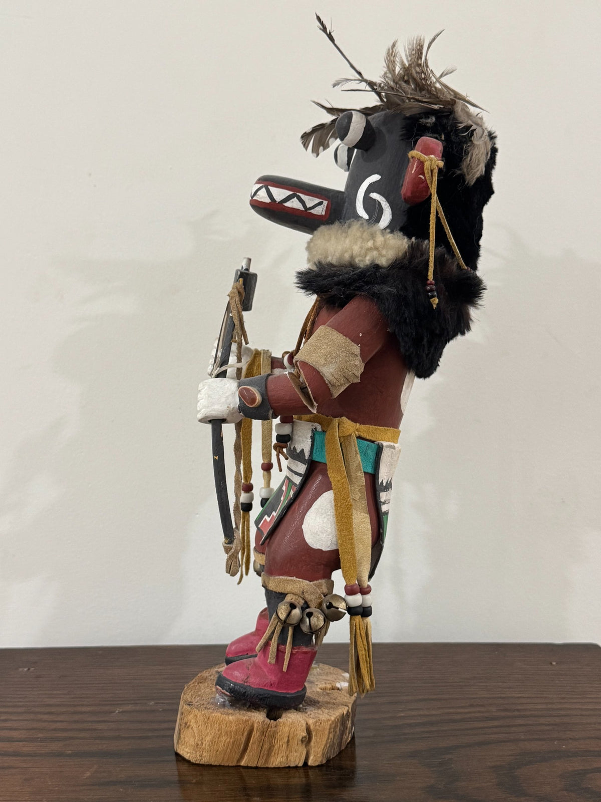 Detail of lower body showing red and pink boots, painted geometric designs in green, red, white, and black patterns