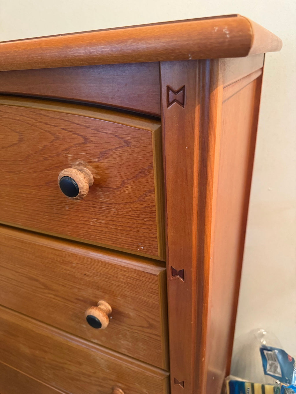 Close view of the rounded top corner, drawer front and knobs