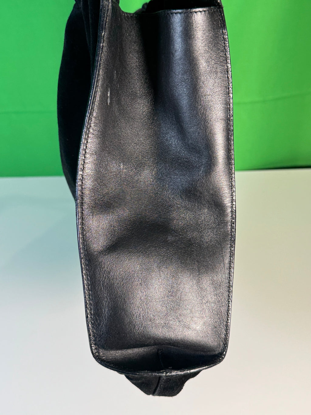 Metallic grey-toned leather side panel with visible seaming detail, green background