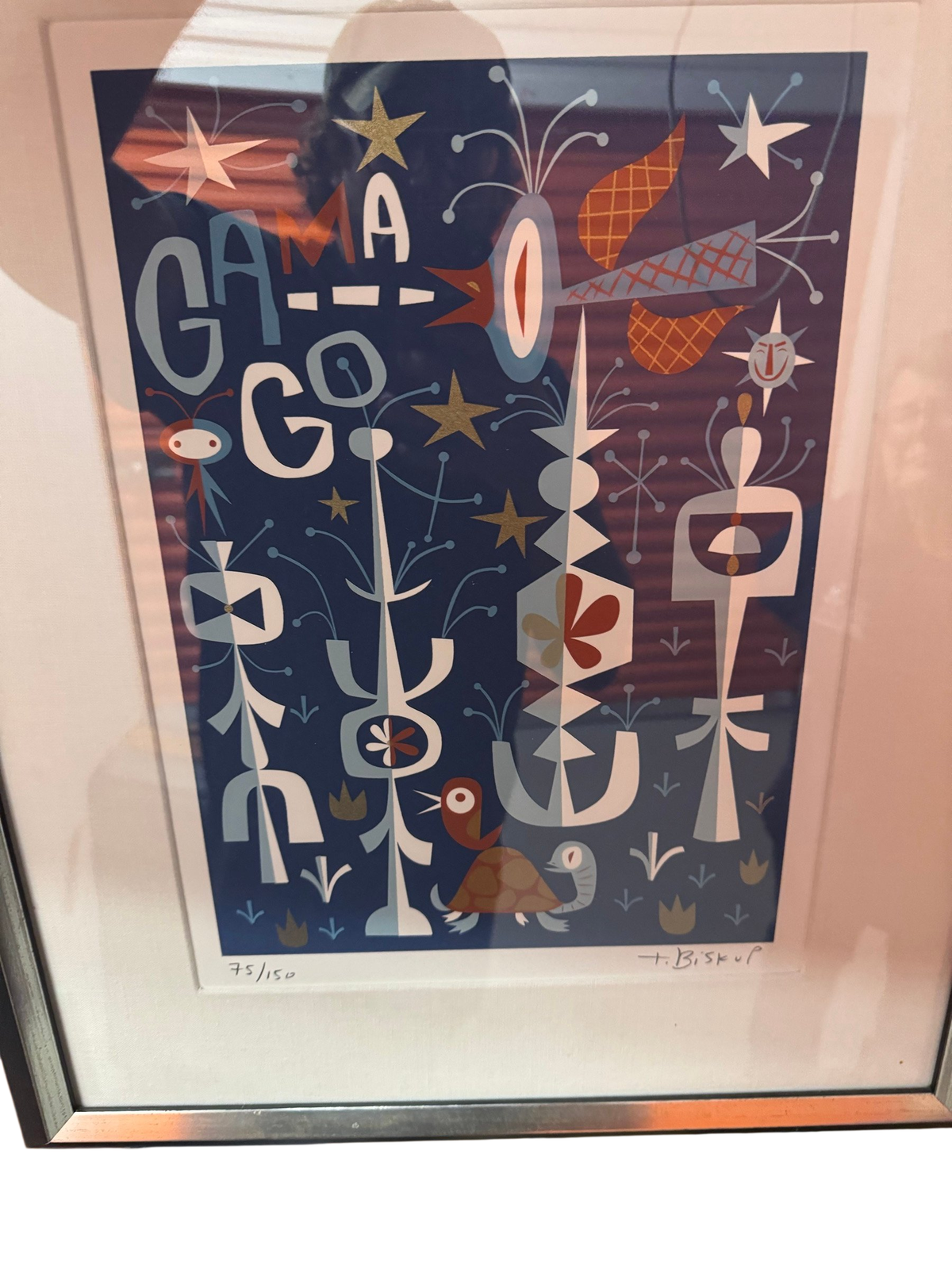 Framed blue screenprint with GAMA-GO lettering in a silver frame with white mat