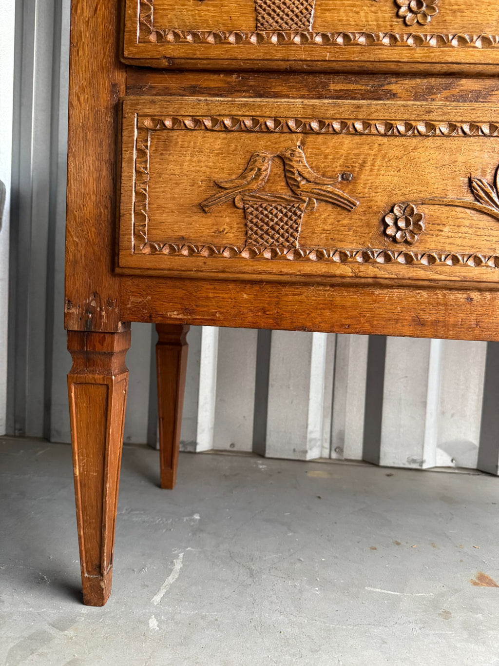 Detail of carved drawer front with ornate brass keyhole plate and wood carving