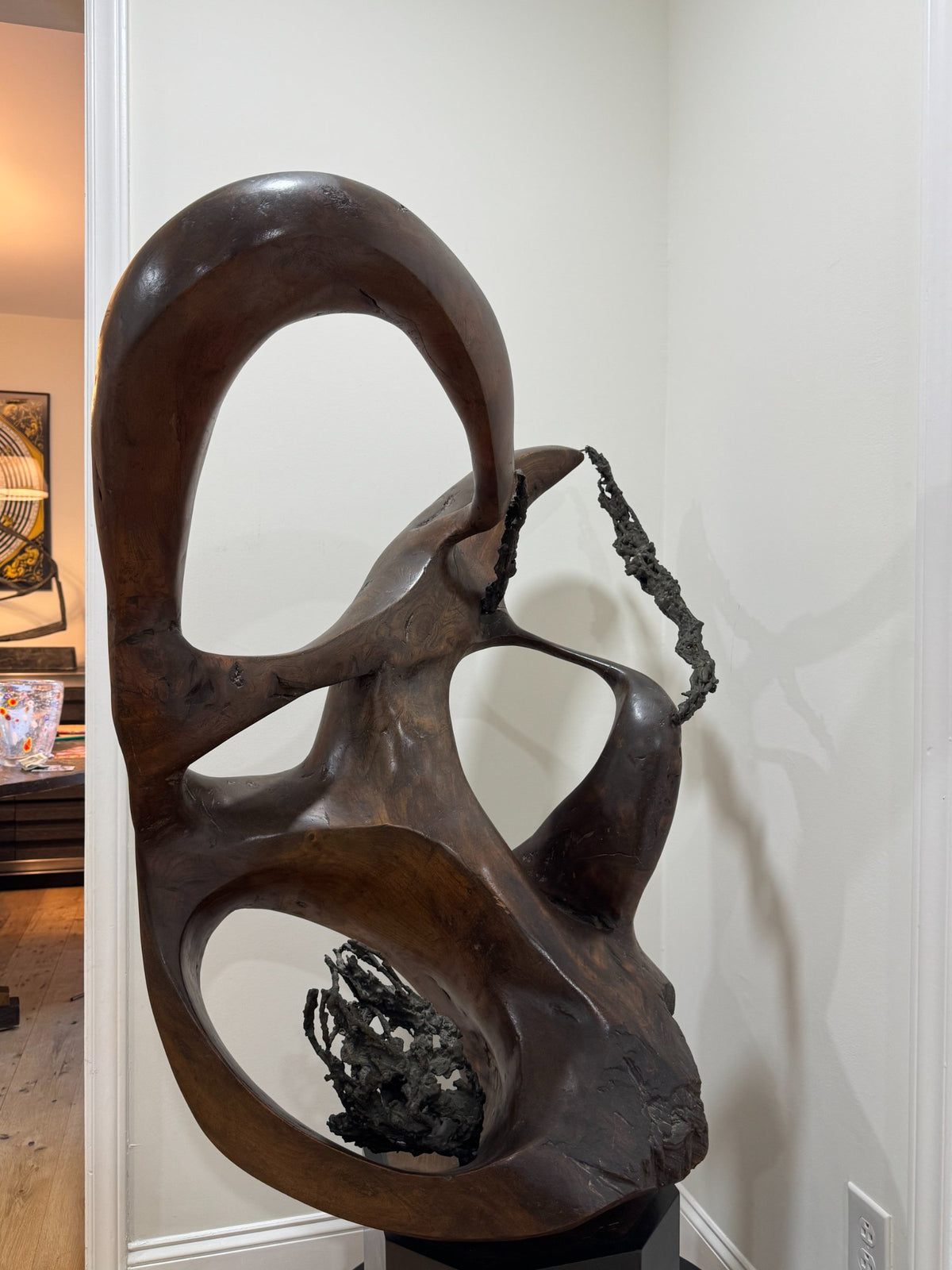 Angled detail view of carved wooden forms showing smooth curves, circular openings, and dark accent material integrated into design