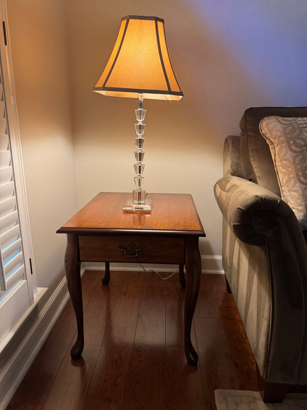 Rectangular cherry finish side table with a single drawer and cabriole legs beside a sofa, topped with a crystal-style table lamp