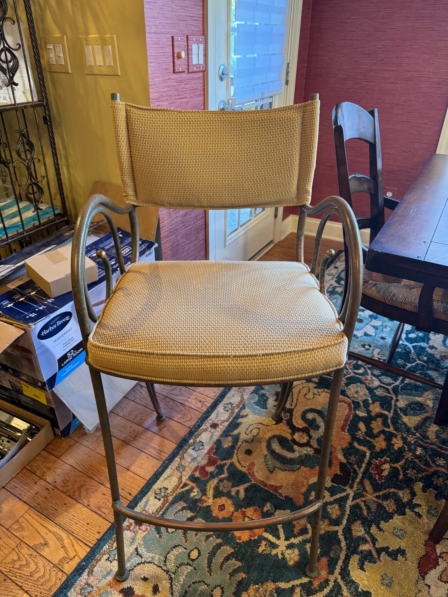 Gold upholstered bar stool with curved metal frame and footrest, front view showing seat and back