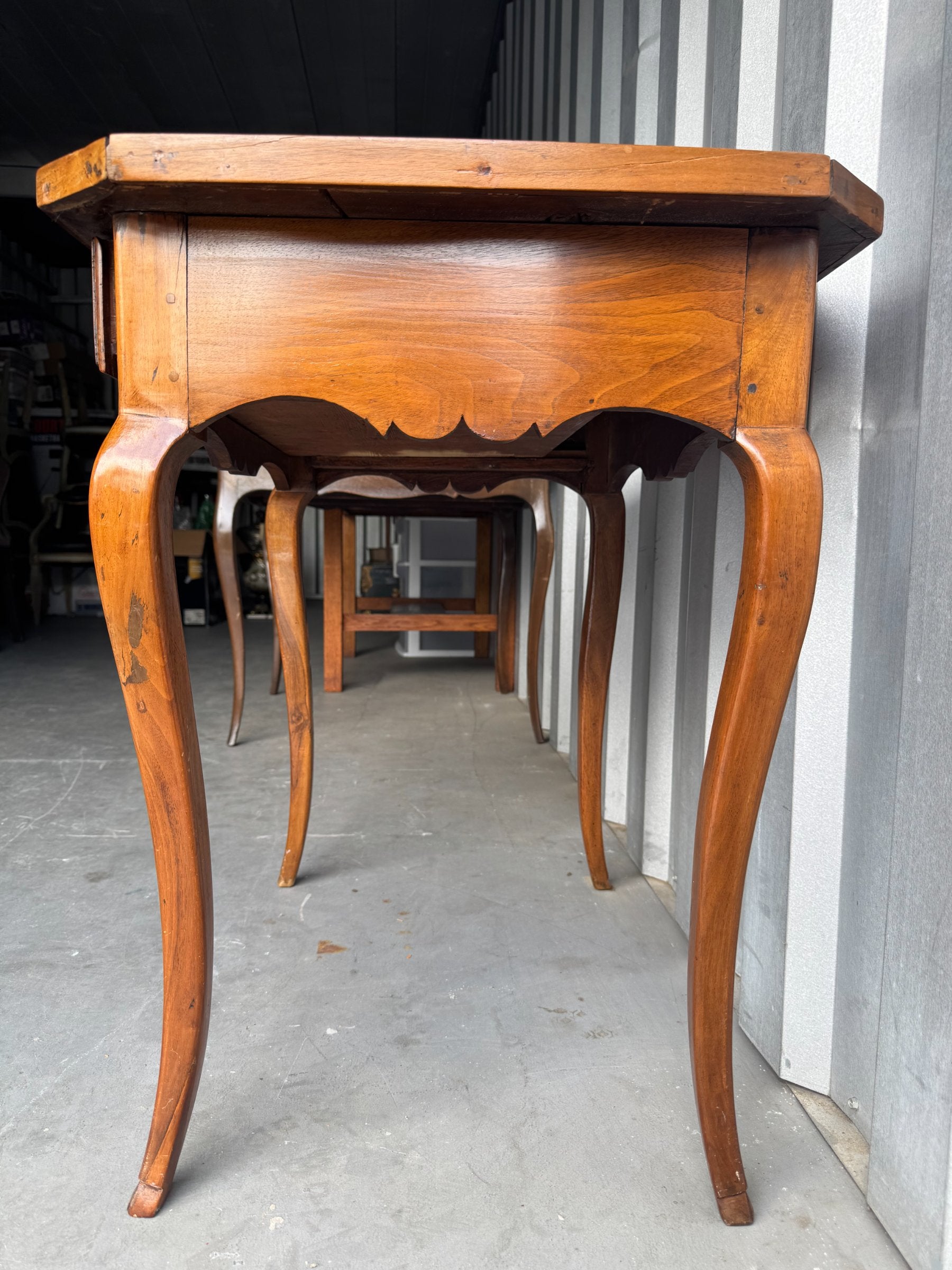 Side view of walnut table showing curved cabriole leg, scalloped apron detail, and overall profile