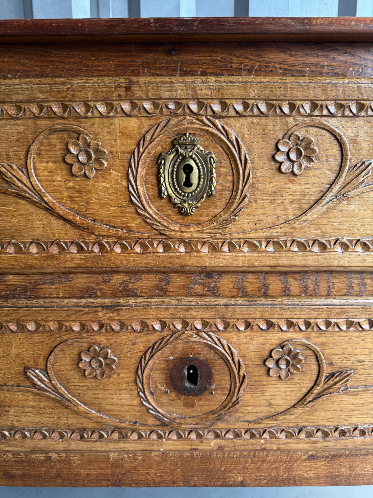 Bottom drawer mechanism and decorative carved border with floral and leaf elements