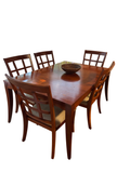 Cherry finish dining table with leaf and six lattice-back chairs in a dining nook with windows